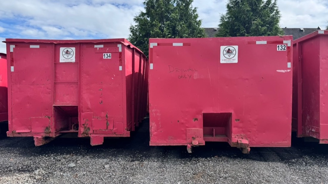 An Eric's Disposal bin marked Drywall Only at a real job site, next to another bin at the Surrey yard